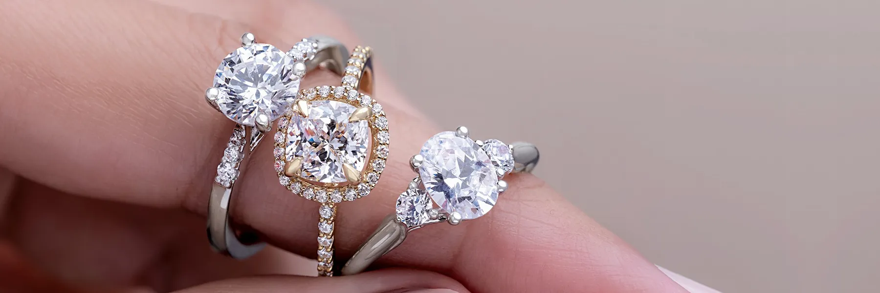 Close-up of three diamond engagement rings in white and yellow gold from LeeBrant Jewelry & Watch Co.