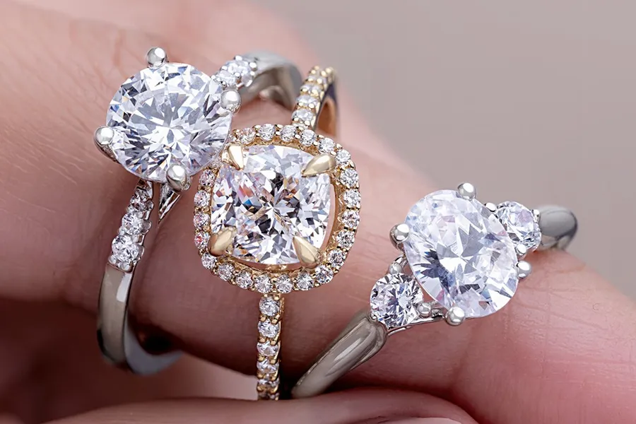 Close-up of three diamond engagement rings in white and yellow gold from LeeBrant Jewelry & Watch Co.