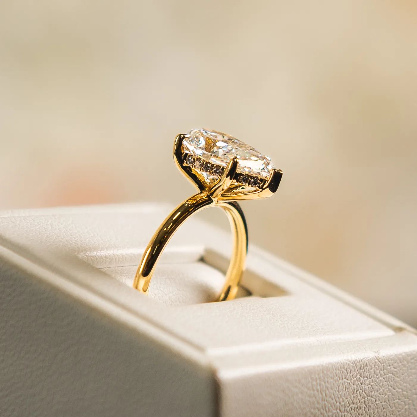 A hand with a diamond engagement ring and pink nails rests on the chest.