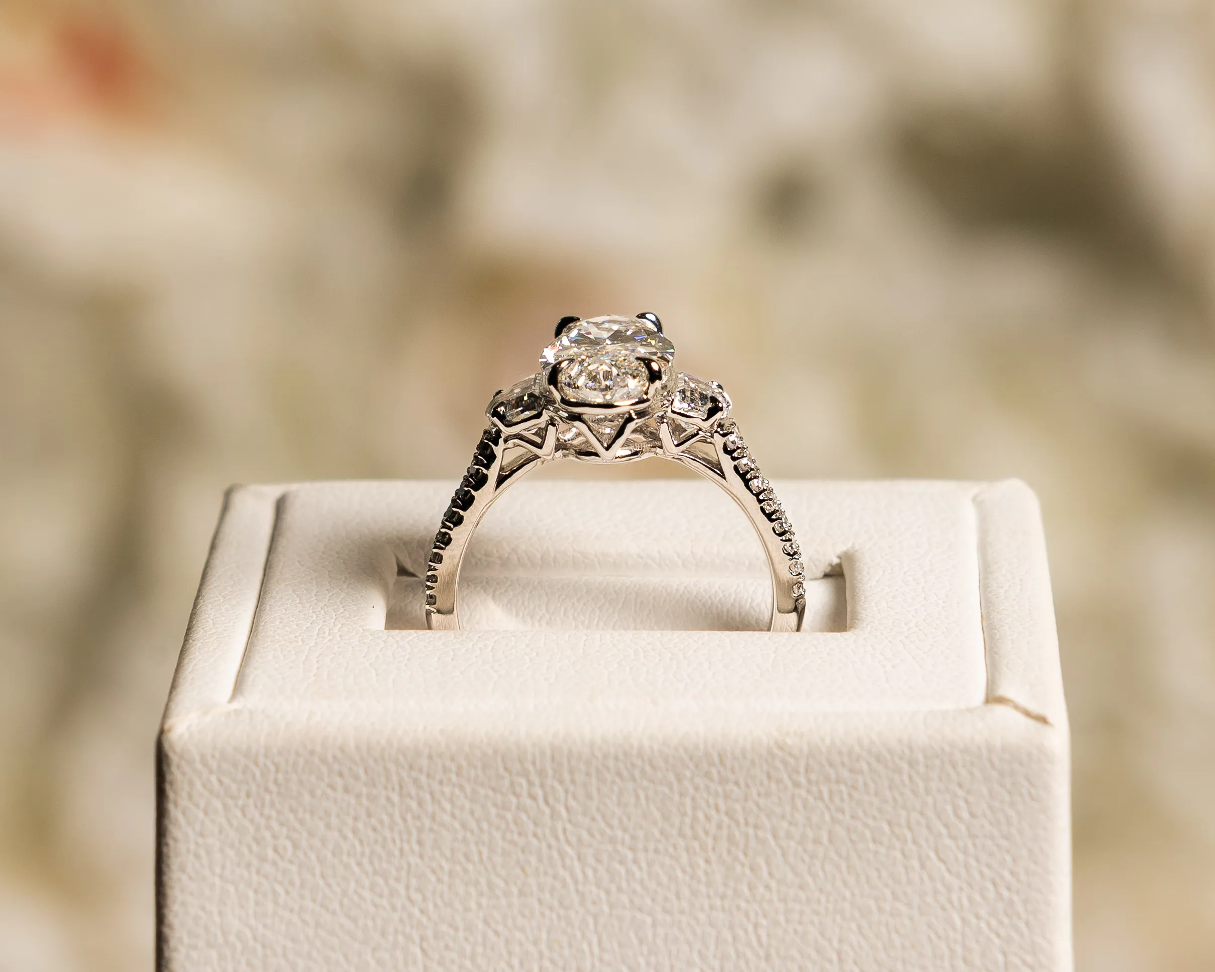 A hand with red nails wearing diamond rings, including an engagement ring.