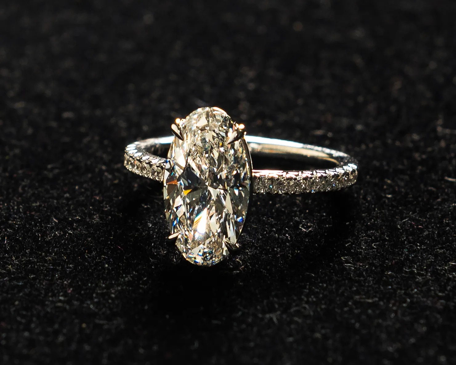 Close-up of a woman's hand with diamond ring and earrings, showcasing fine jewelry.
