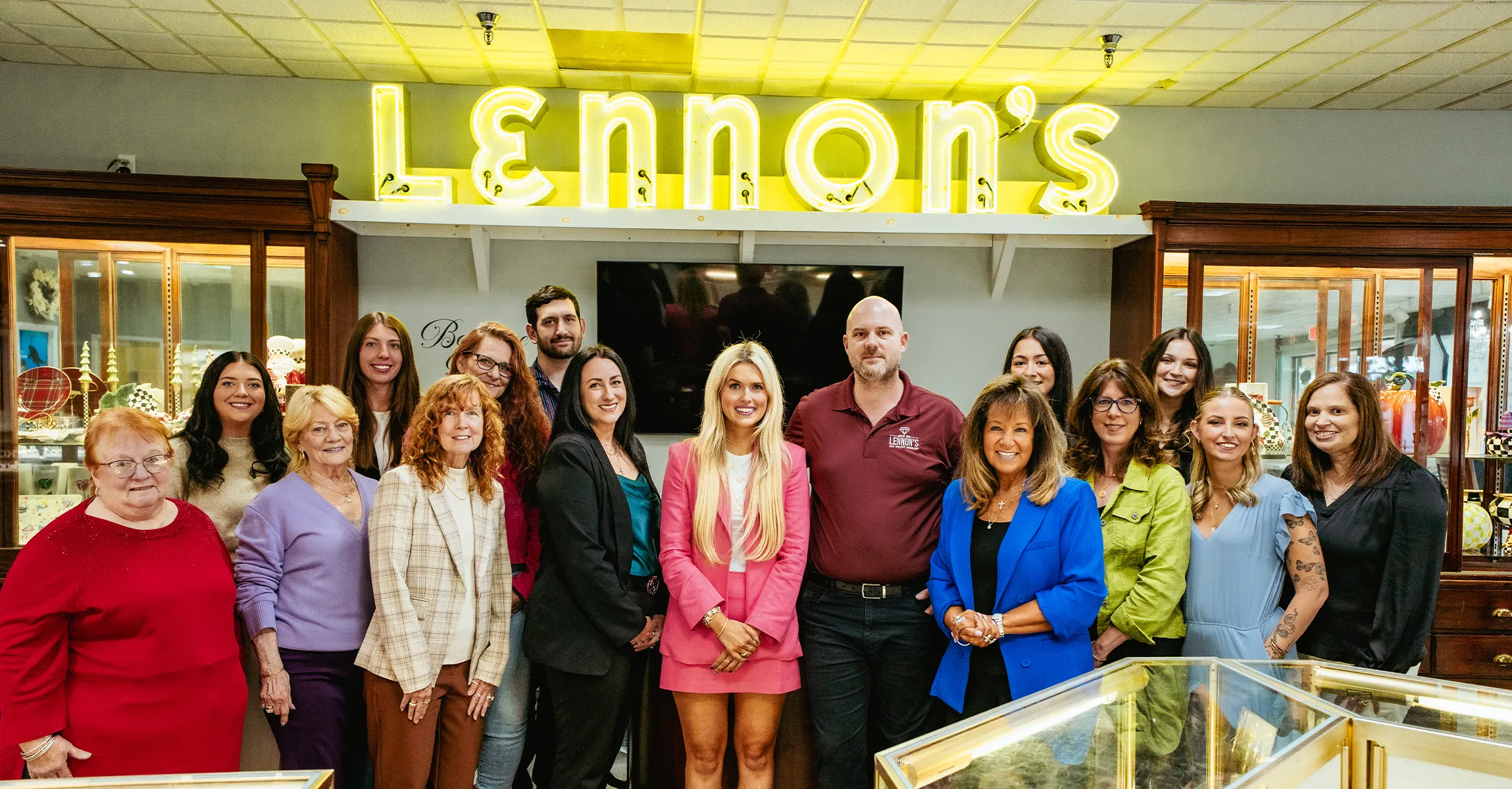 Group of people smiling in front of Lennon's jewelry store sign. Read More about their testimonials.