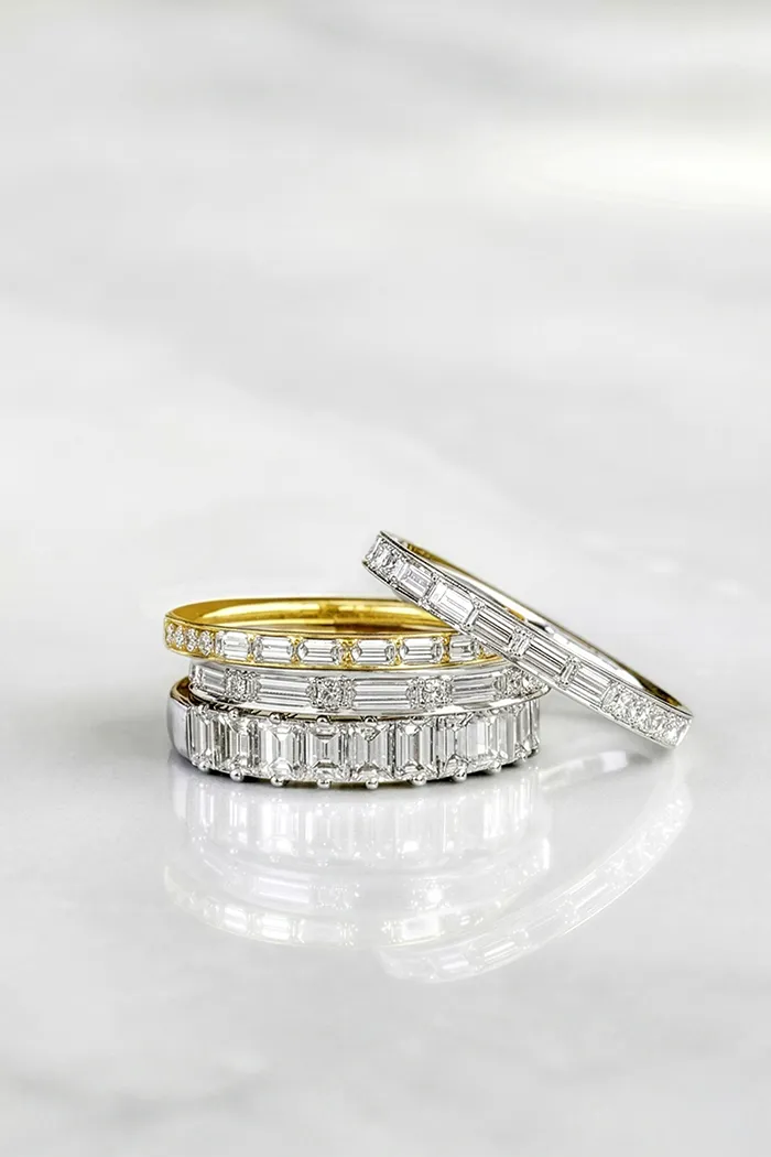 Three elegant diamond-studded rings stacked on a marble surface.
