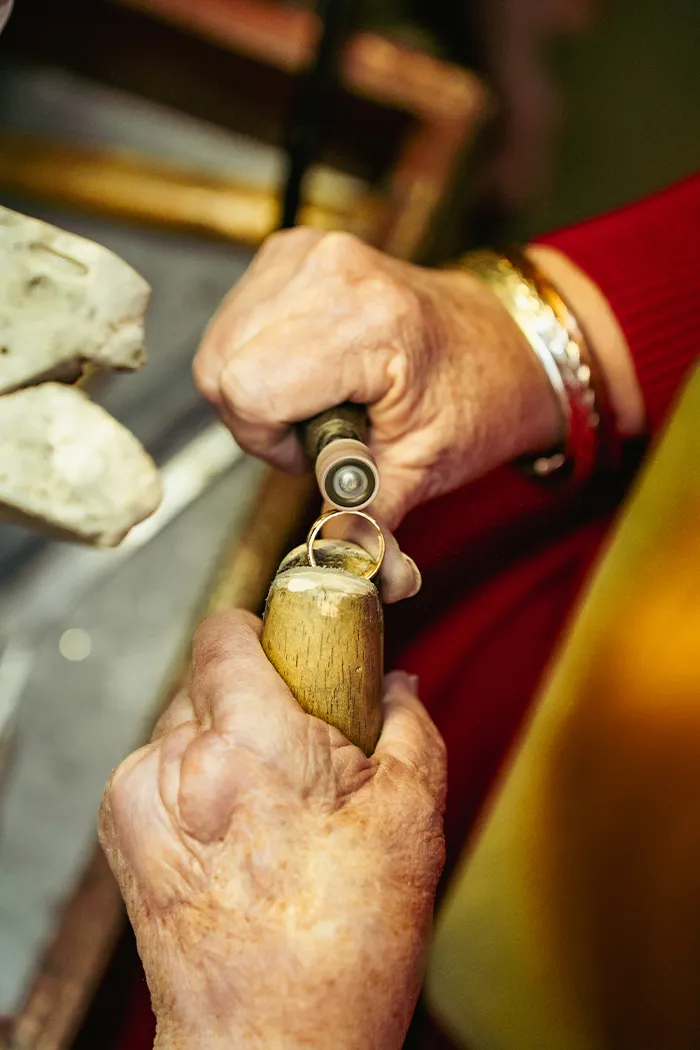 Jeweler's hands working on a ring with tools, showcasing craftsmanship.