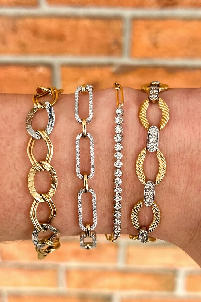 Hands with diamond rings and bracelets on a burgundy fur coat.