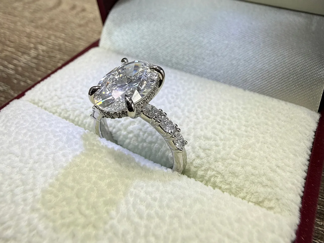 A large diamond engagement ring in a white jewelry box.