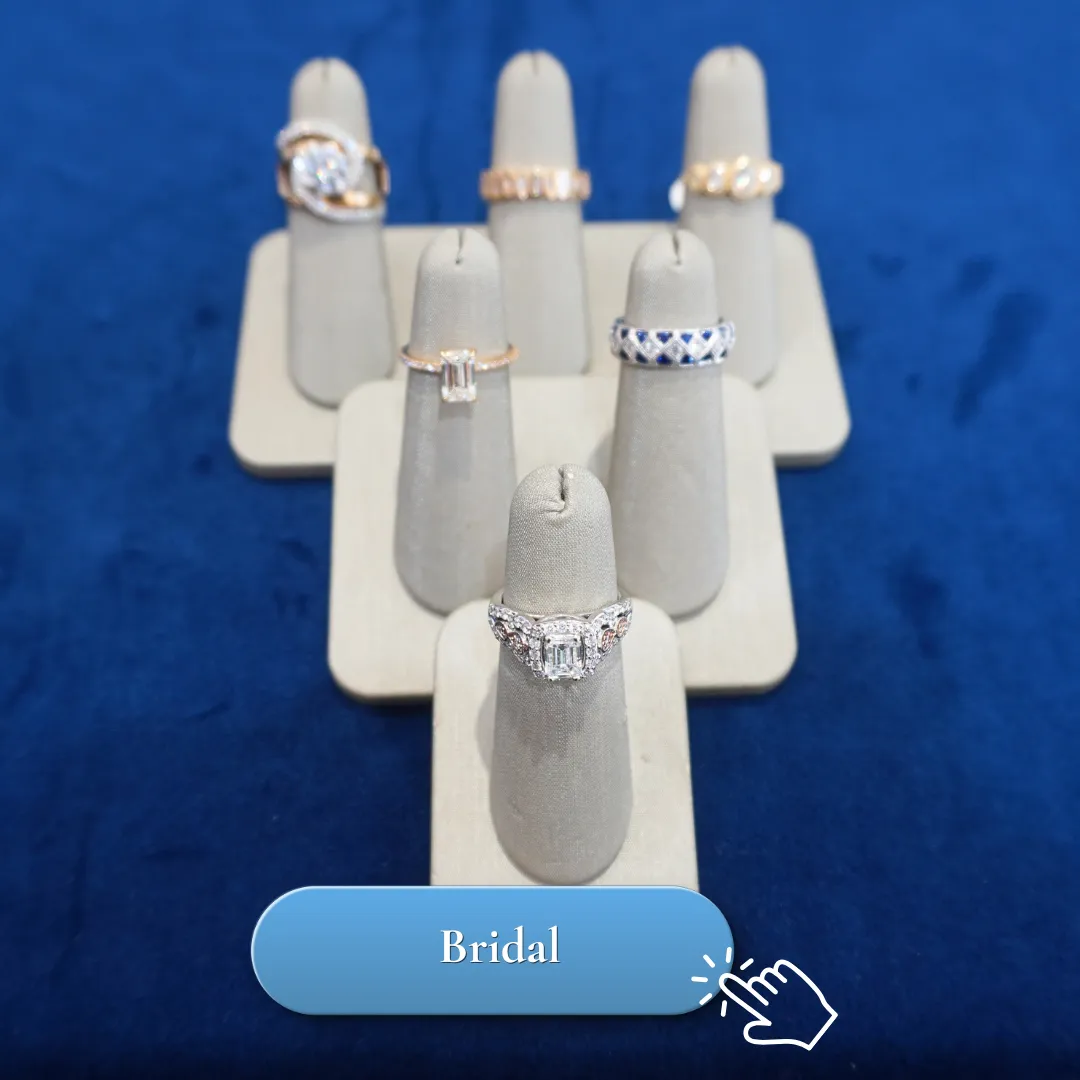 Elegant diamond rings displayed on beige stands against a blue background.