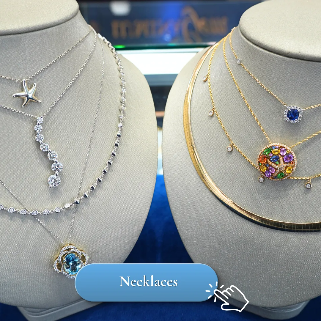 Elegant necklaces displayed on two busts, featuring diamonds and colorful gemstones.