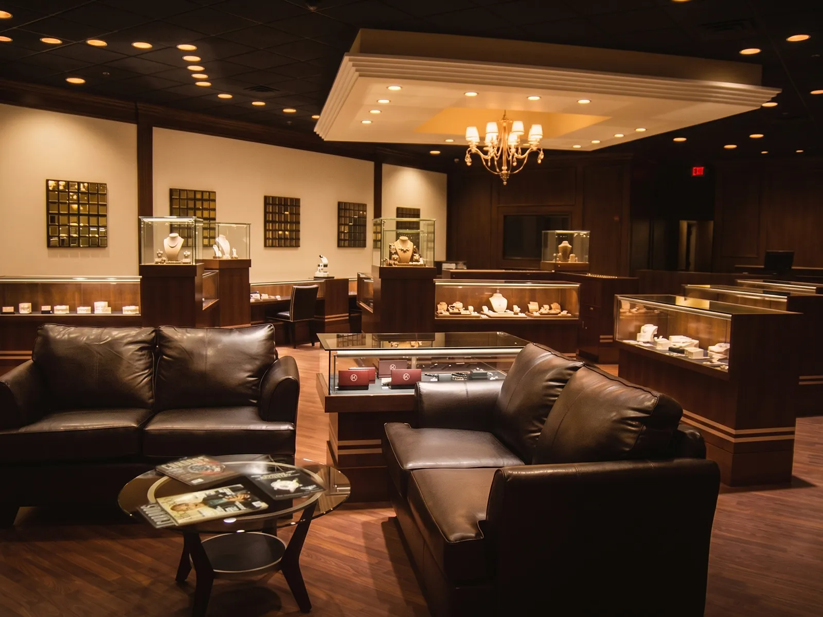 Elegant jewelry store interior with display cases, leather sofas, and a chandelier.