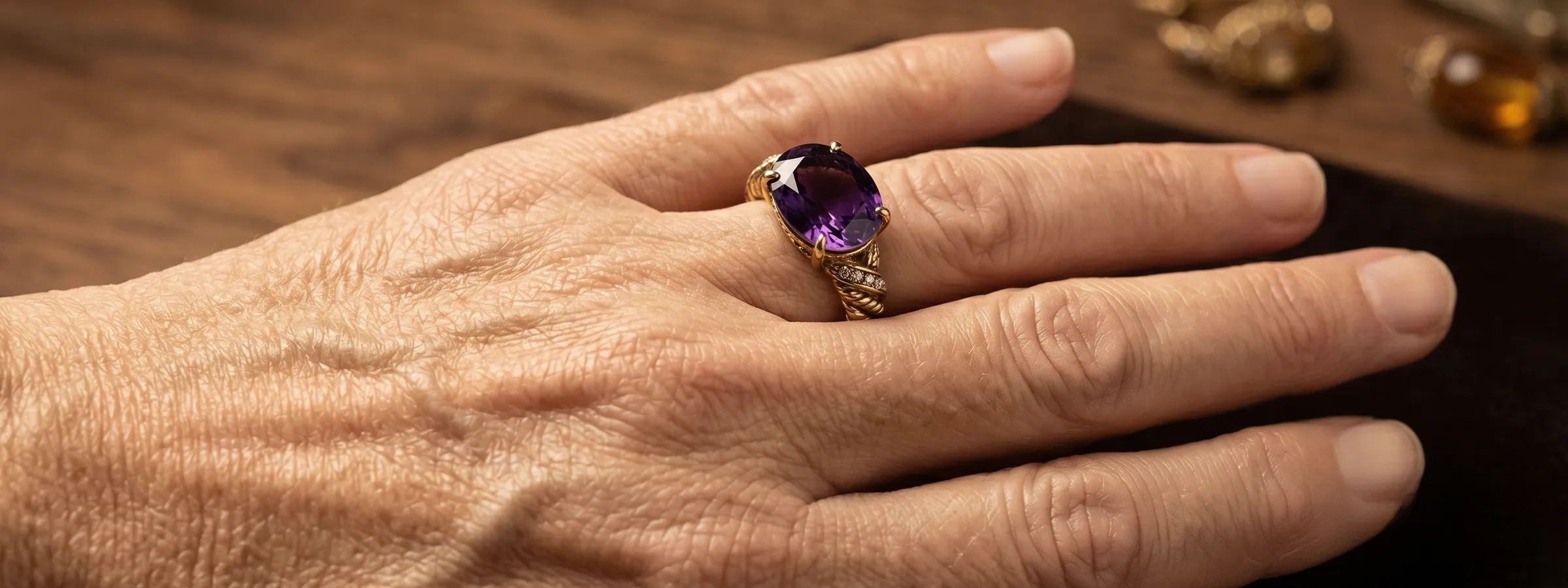 A hand wearing a gold ring with a large purple gemstone.