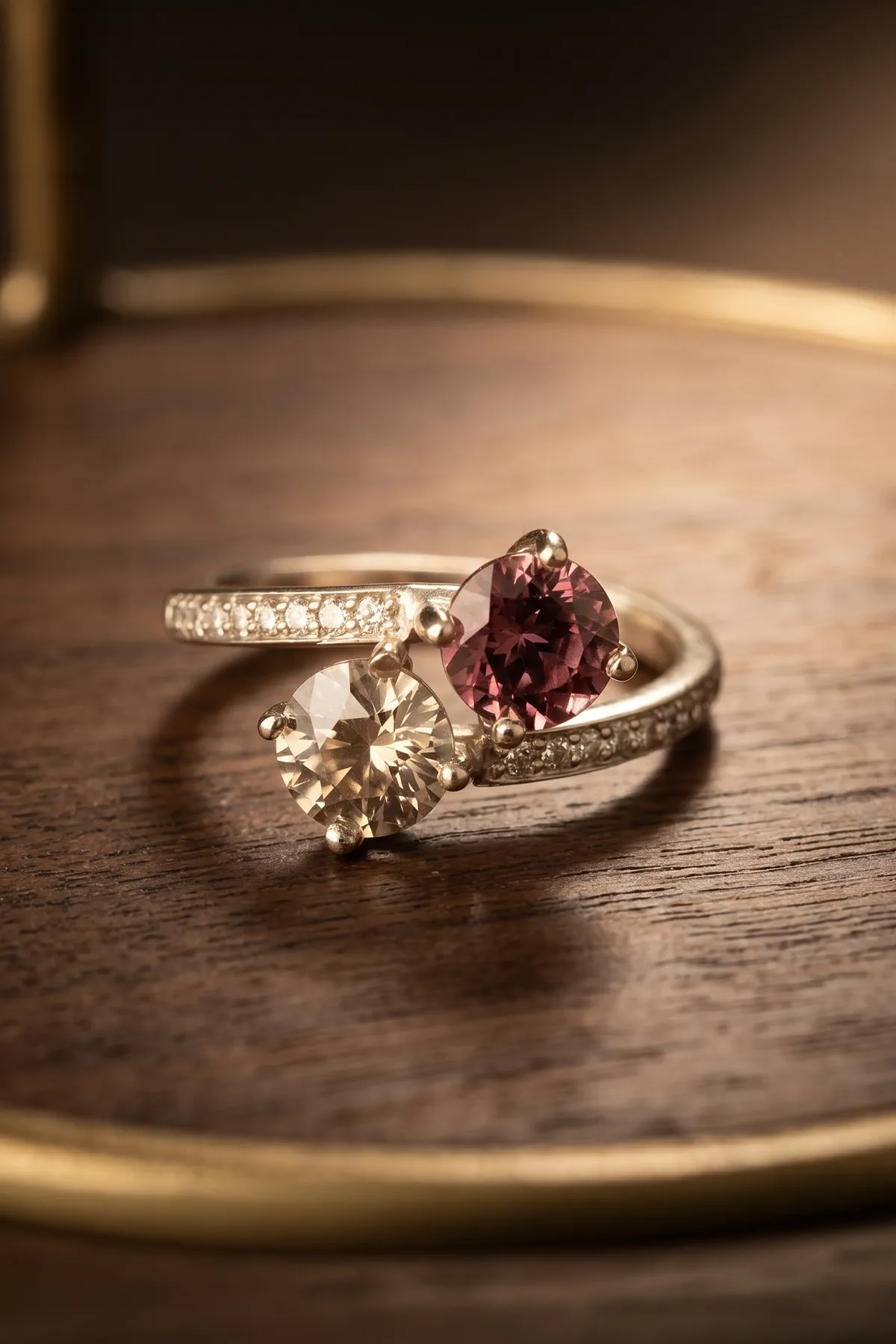 Two-stone ring with pink and clear gems on a wooden surface, crafted by Marshall's Jewelers, Bellingham MA.