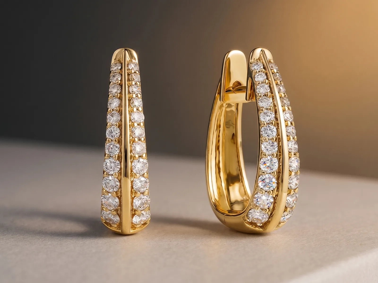 Gold hoop earrings with rows of sparkling diamonds displayed on a soft surface.