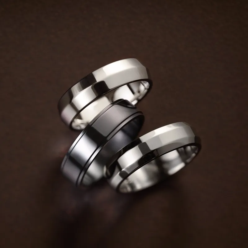 Three classic metal wedding bands displayed on a dark background, showcasing different finishes and styles.