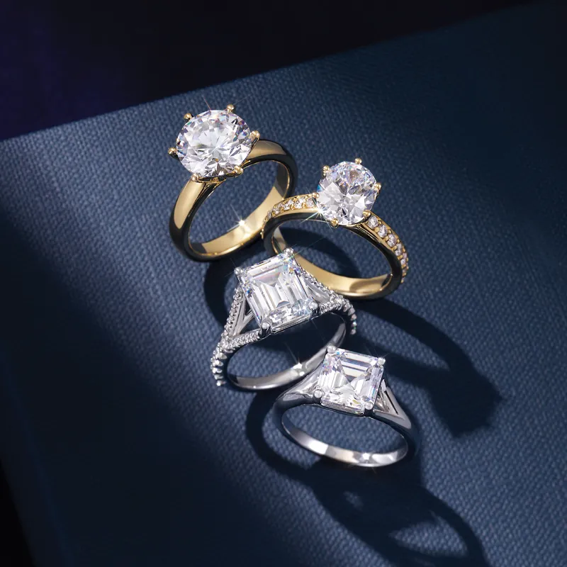 Four elegant engagement rings featuring round and emerald-cut diamonds, set in gold and silver.
