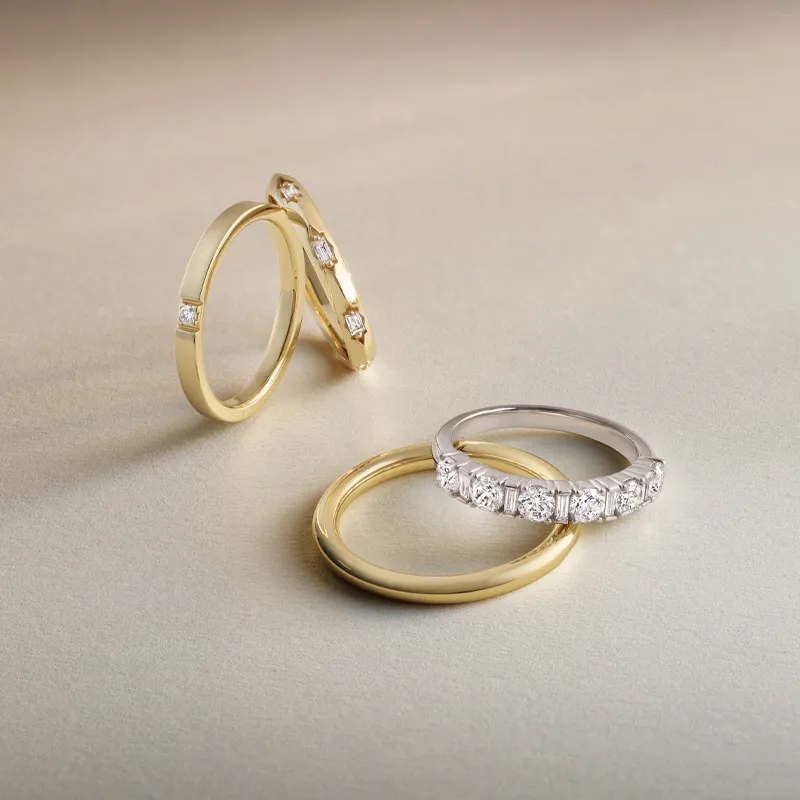 Three elegant gold and silver rings, featuring diamonds, displayed on a soft background.