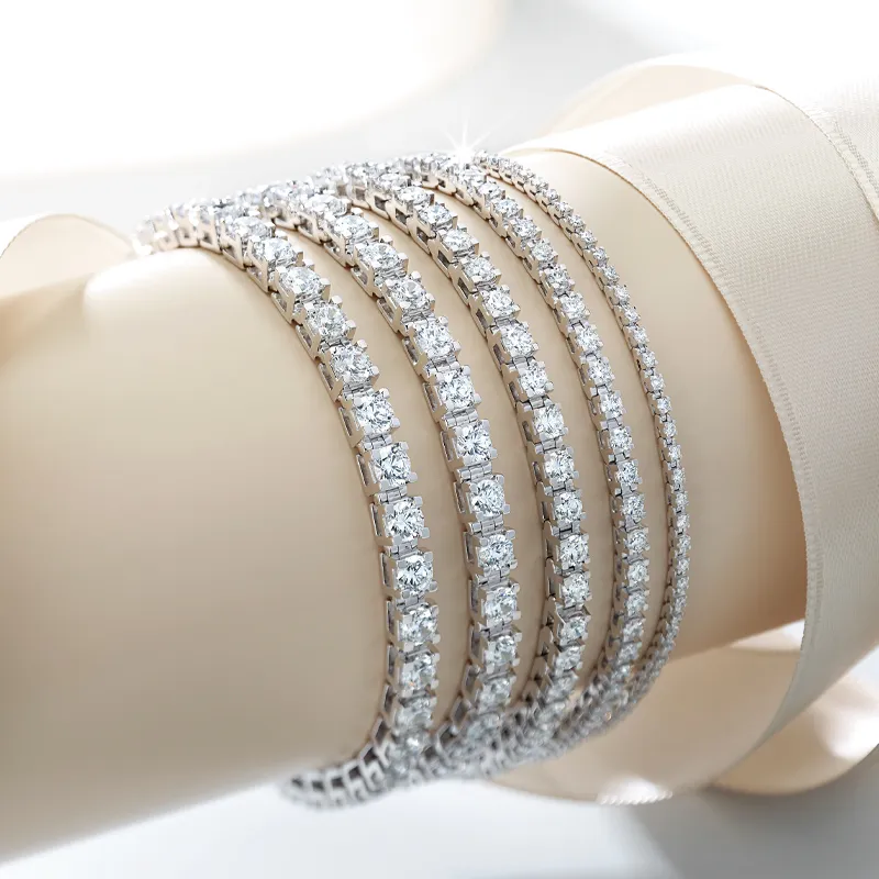 Four elegant diamond tennis bracelets displayed on a wrist, showcasing their sparkle and design.