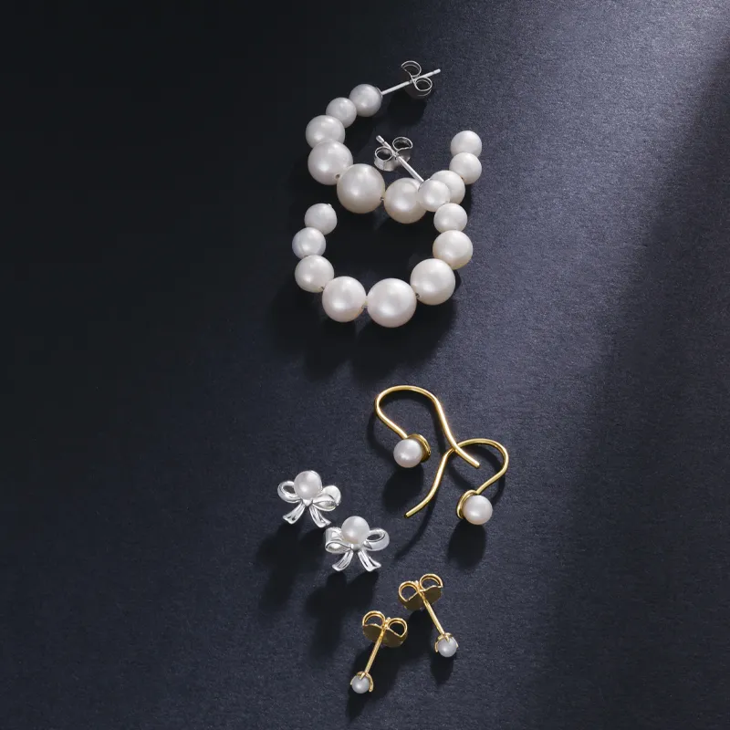 Elegant assortment of pearl earrings and studs on a dark background.