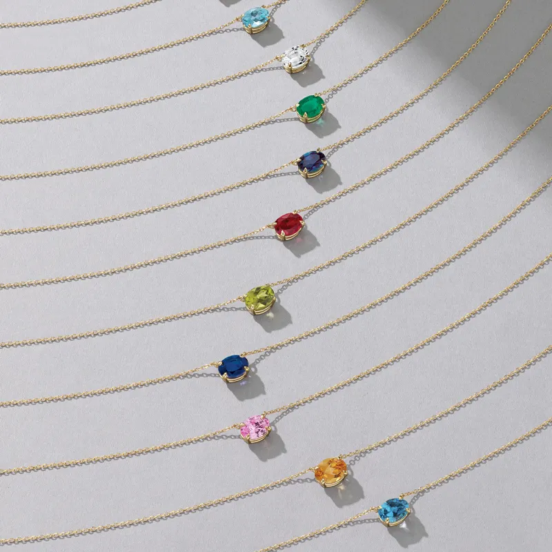 Colorful birthstone necklaces displayed on gold chains, showcasing various gemstones.