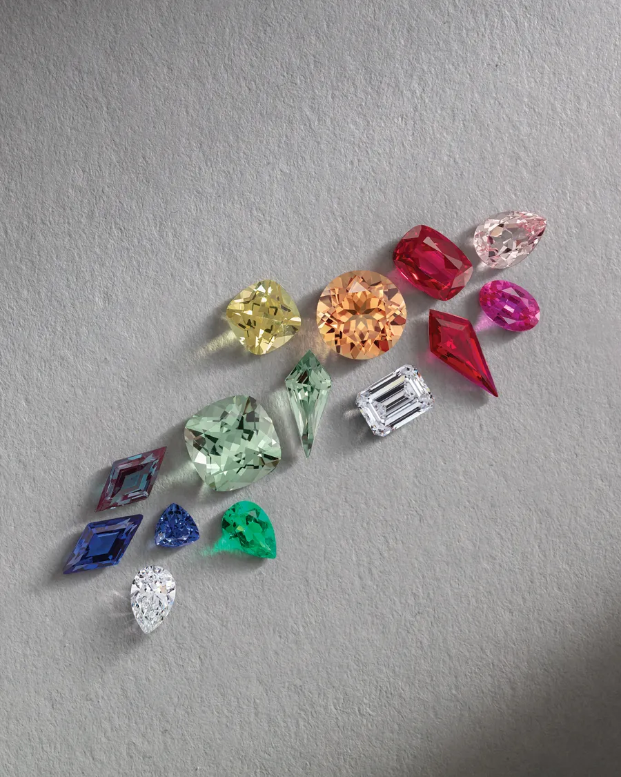 Colorful loose gemstones arranged on a gray background.