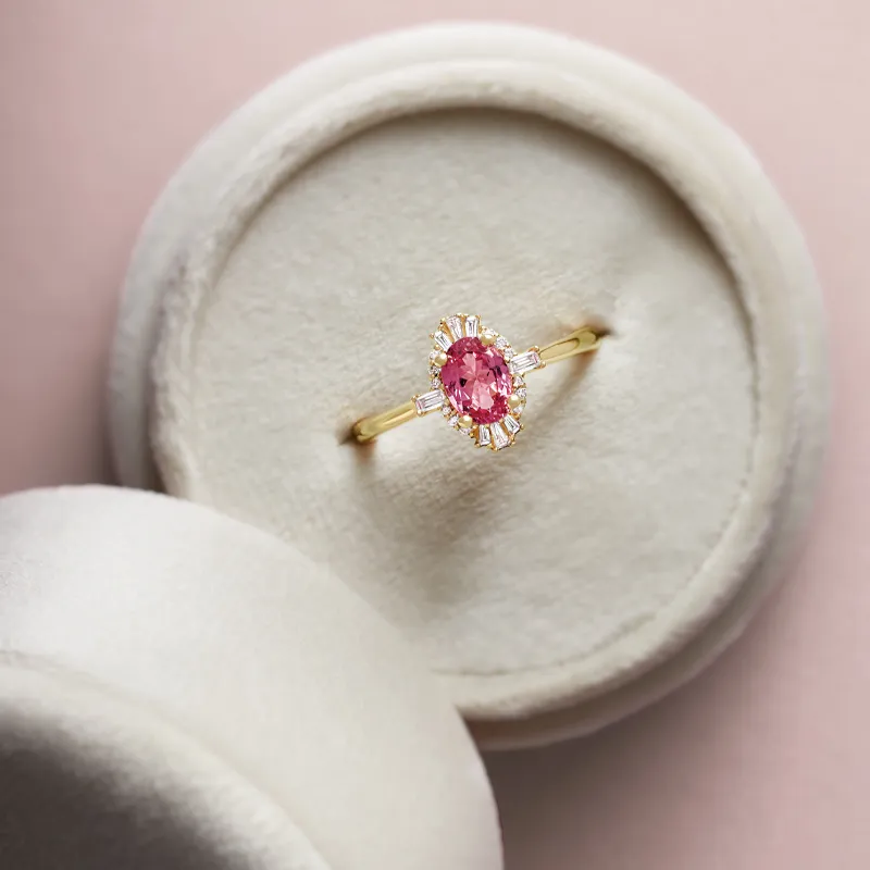 Gold ring with a pink gemstone and diamond accents, displayed in a velvet ring box.