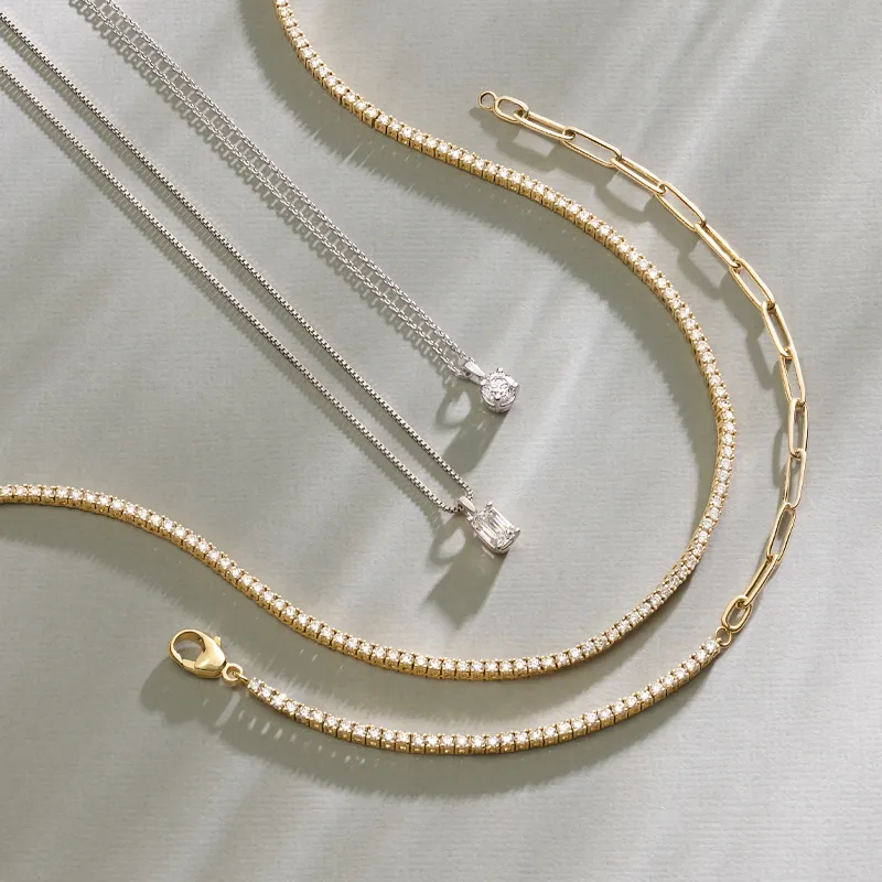 Elegant gold and silver necklaces displayed on a soft surface, showcasing fine jewelry.