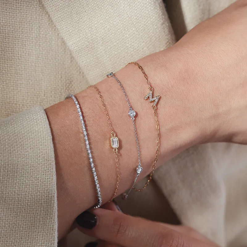 Four elegant bracelets on a wrist, featuring diamonds and gold accents.