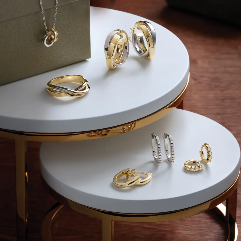 Elegant gold and silver earrings and rings displayed on a stylish table.