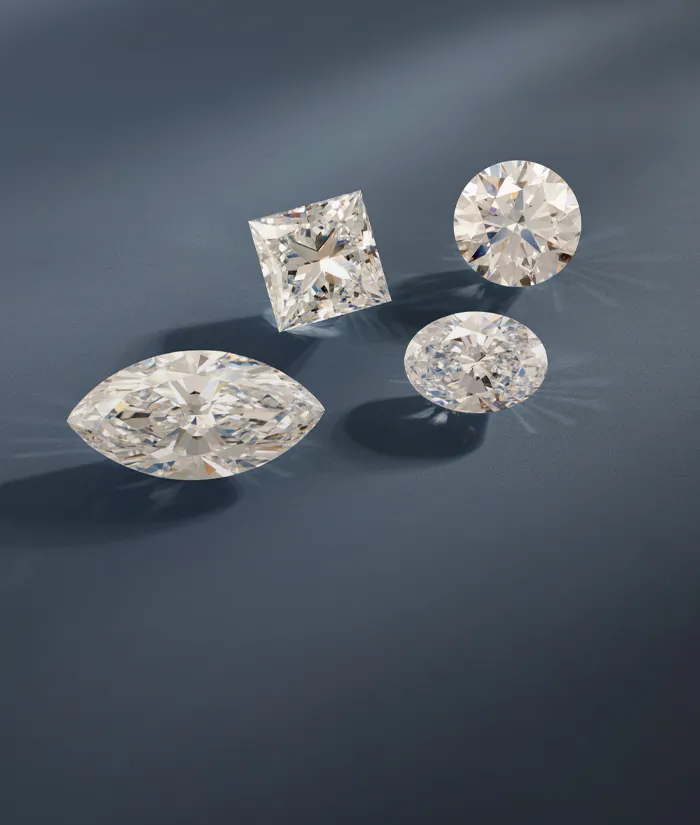 Four sparkling diamonds in various cuts on a dark blue background, showcasing elegance and luxury.