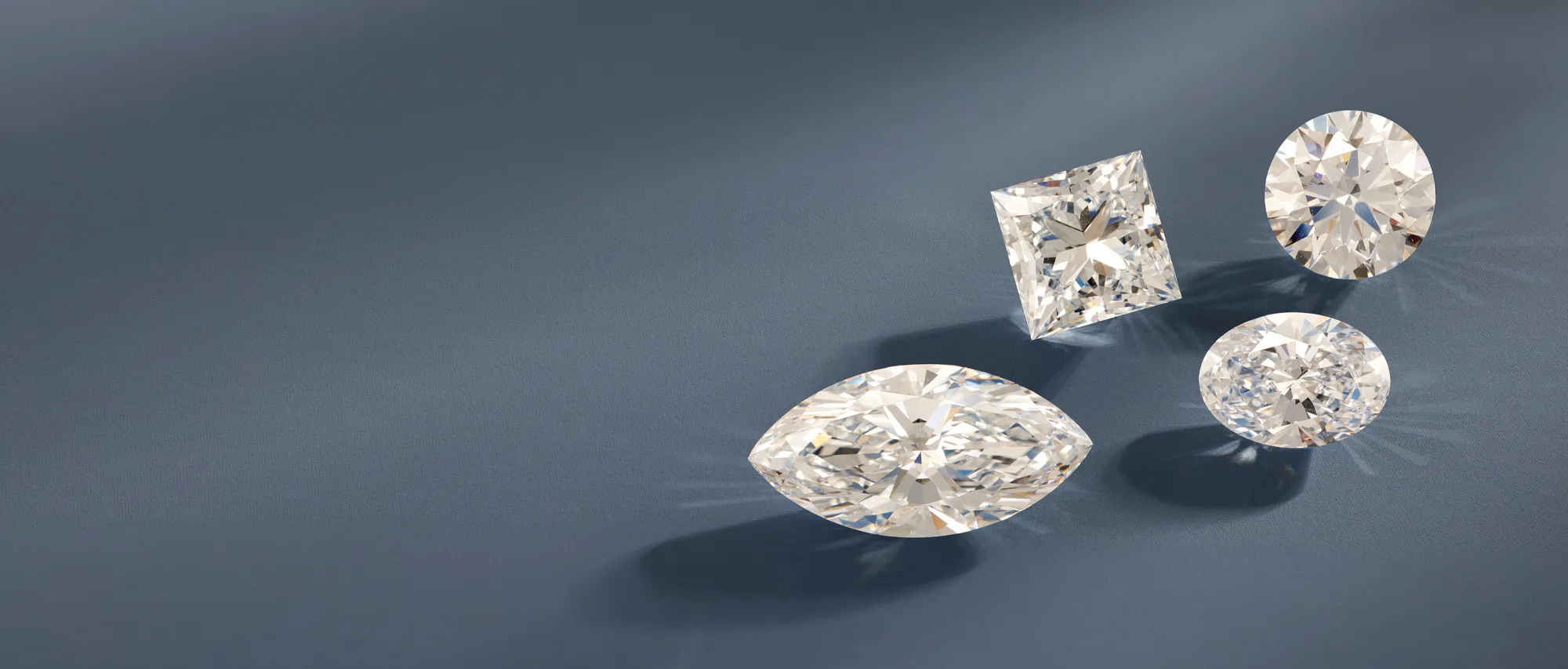 Four sparkling diamonds in various cuts on a dark blue background, showcasing elegance and luxury.