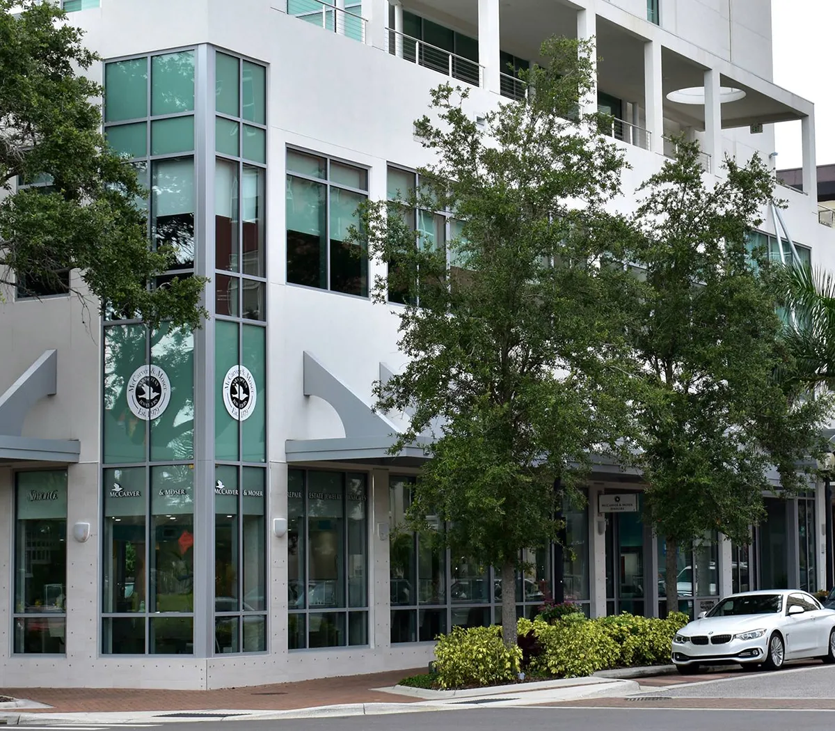 Modern building with large windows and trees in front, housing McCarver Moser Jewelry Store.