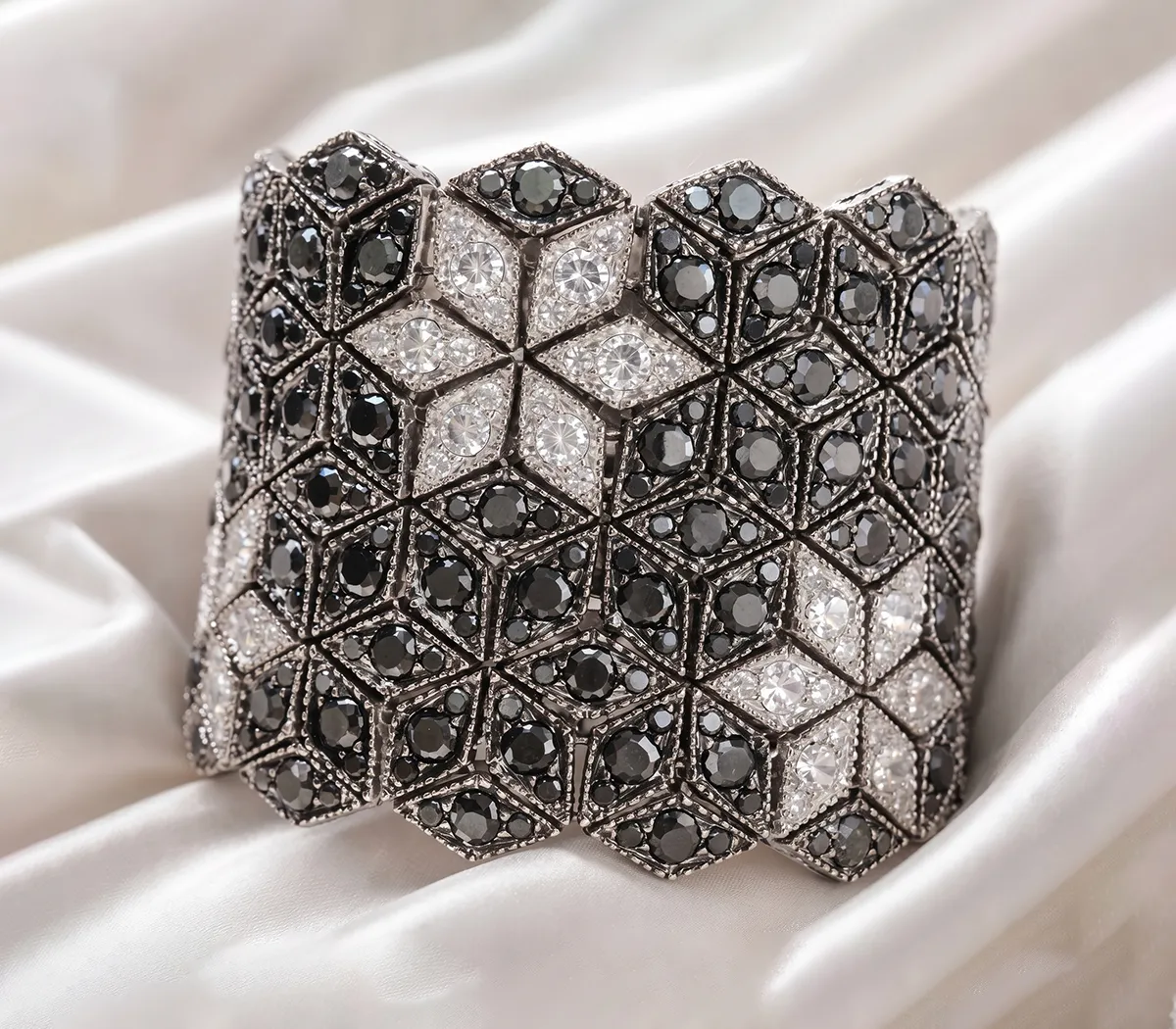 Intricate black and white diamond bracelet on white fabric background.