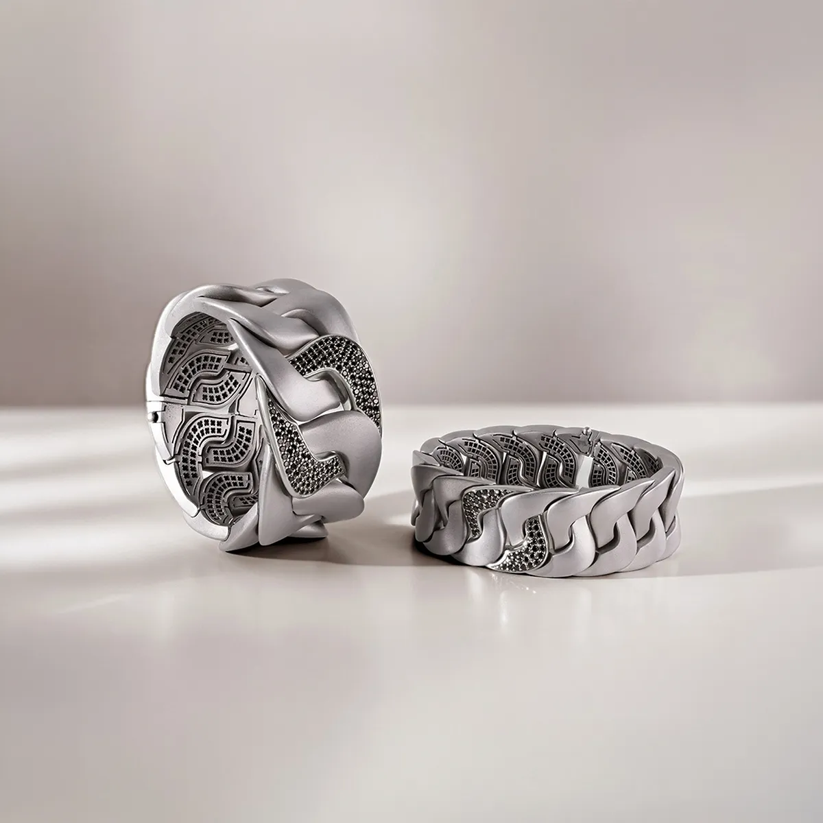 Silver men's bracelets with intricate patterns on a white surface.