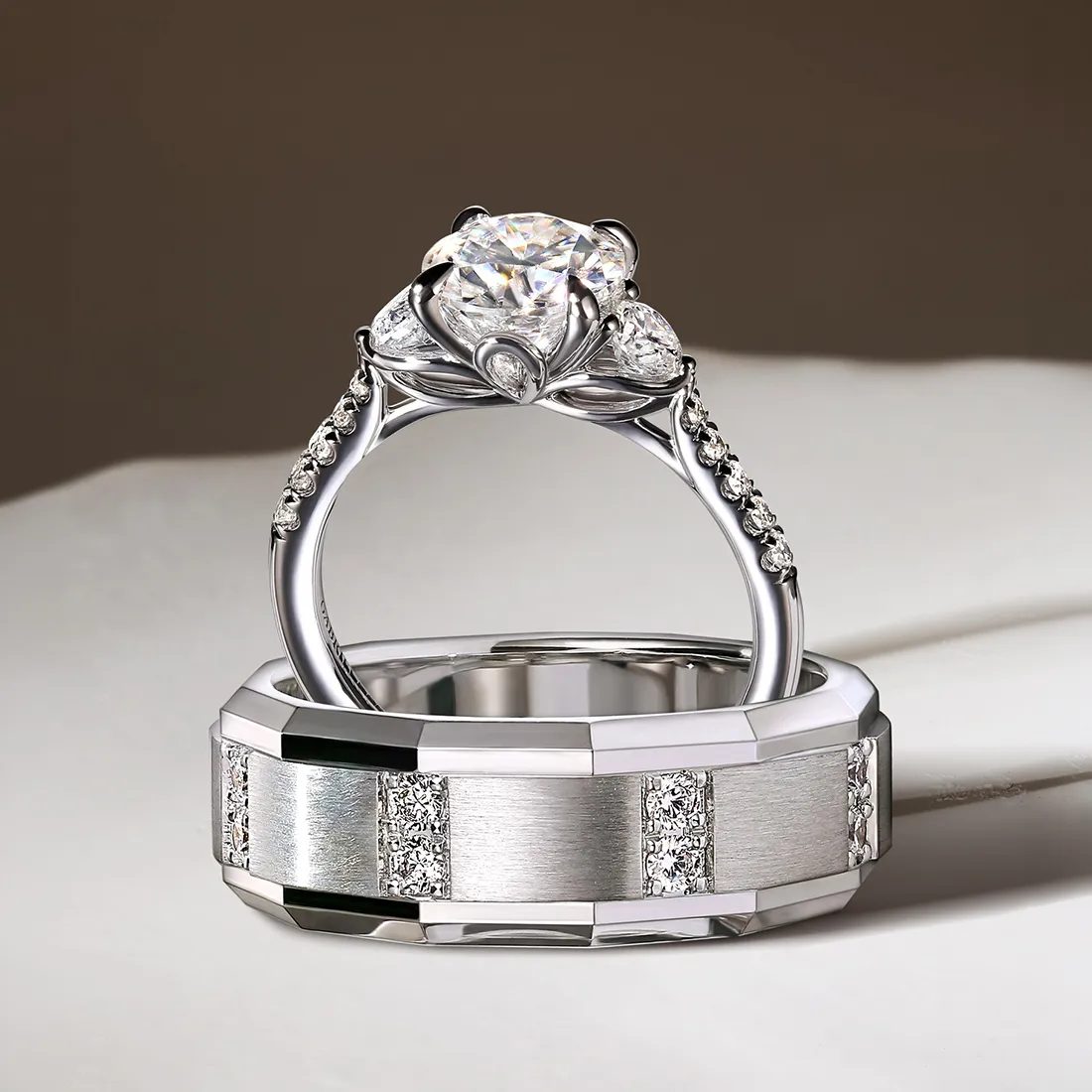 Elegant diamond engagement ring and wedding band set on a reflective surface.