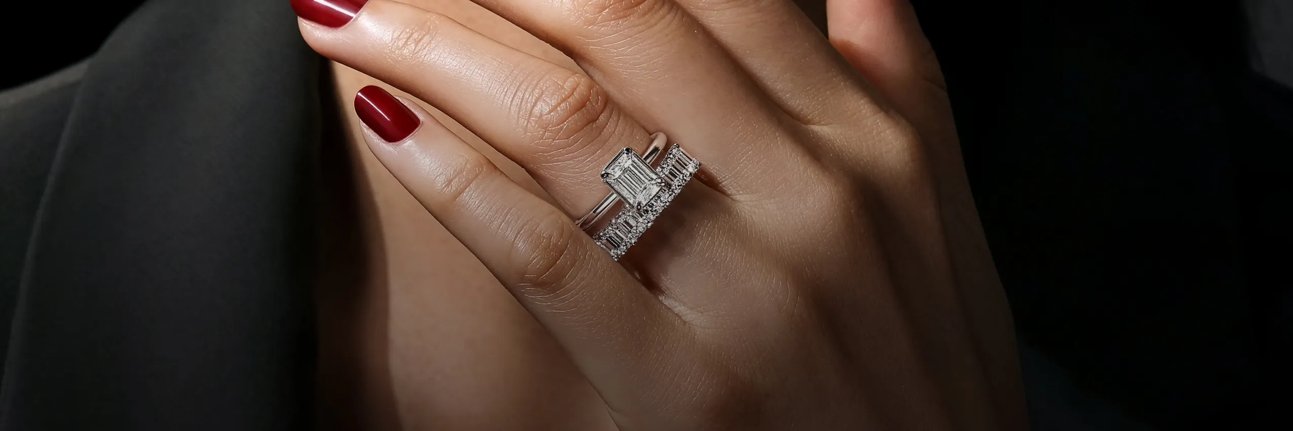 Close-up of a hand with red nails wearing a diamond ring. Shop Gabriel & Co.