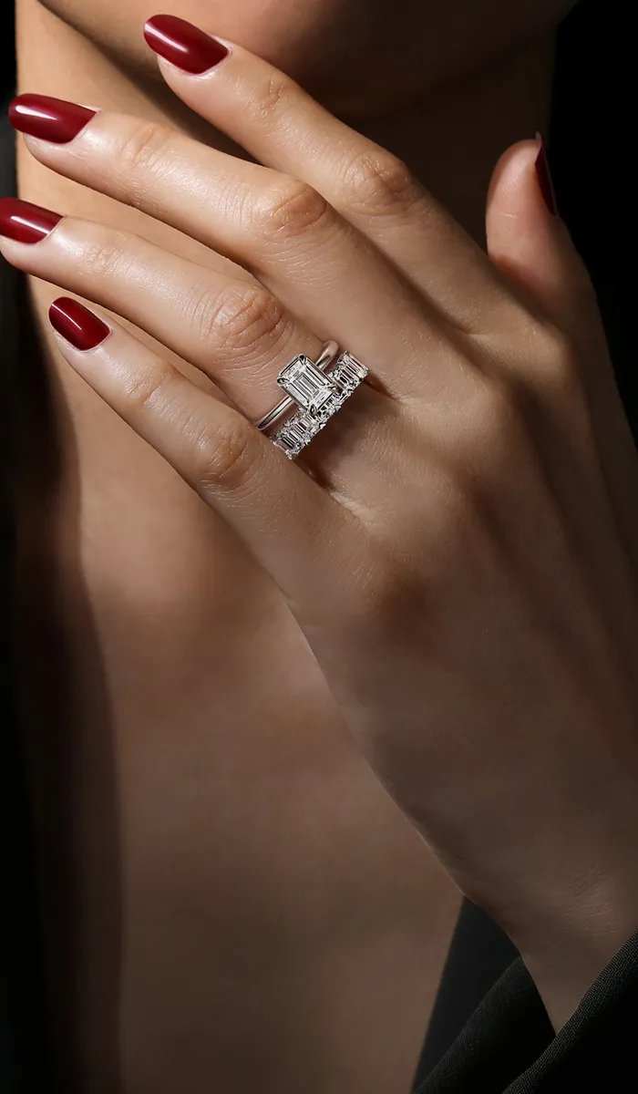 Close-up of a hand with red nails wearing a diamond ring. Shop Gabriel & Co.