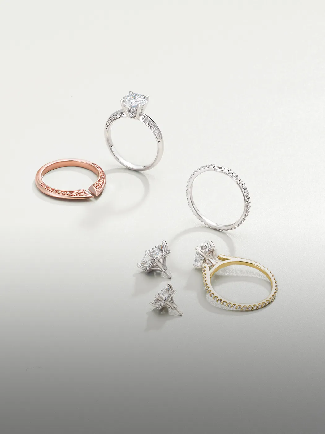 Engagement ring settings in various metals displayed on a light background. Explore settings at McGee & Company.