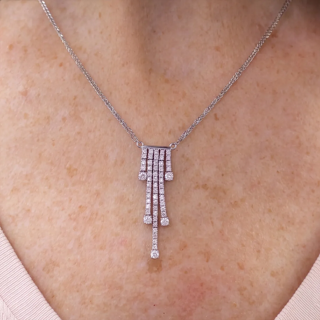 Diamond pendant necklace with cascading design on a person's neck.