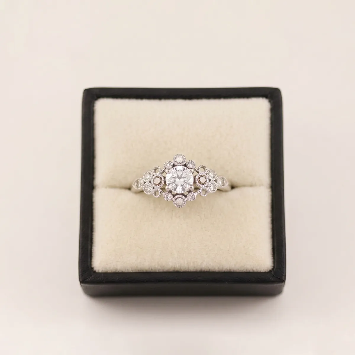 Elegant diamond ring in a black box, showcasing intricate design and central stone.