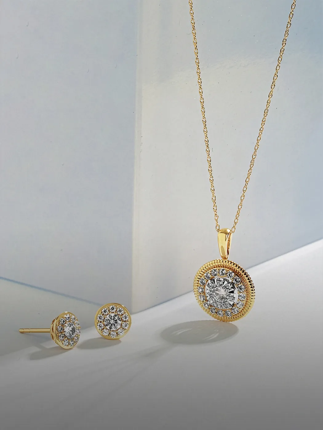 Gold necklace and earrings with diamond accents displayed on a light surface.