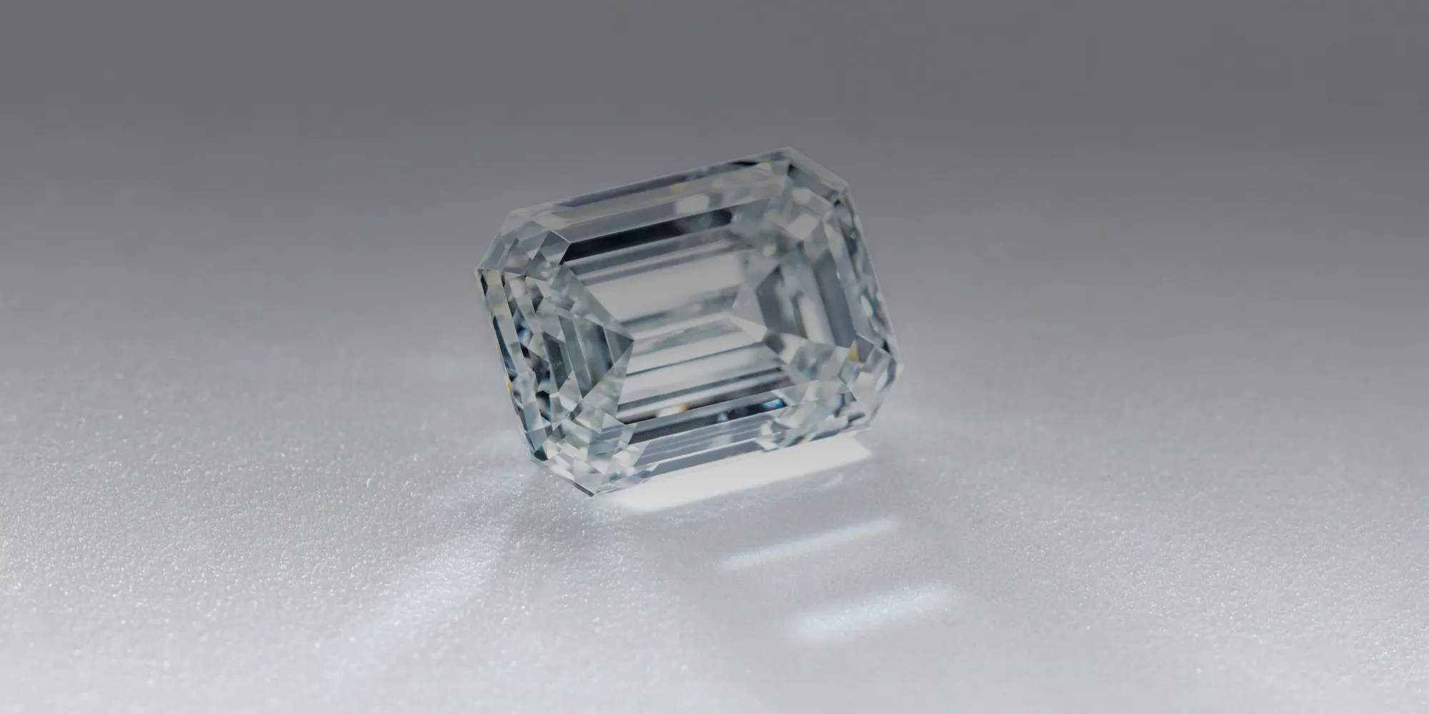 Emerald-cut diamond on a reflective surface.