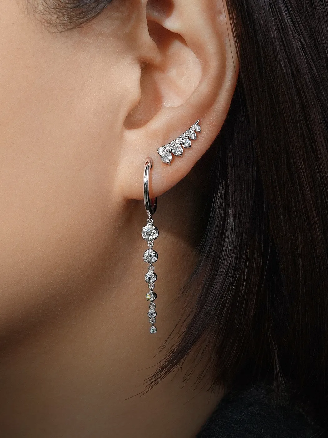 Diamond earrings with a cascading design worn on an ear. Explore more at McGee & Company Fine Jewelers.