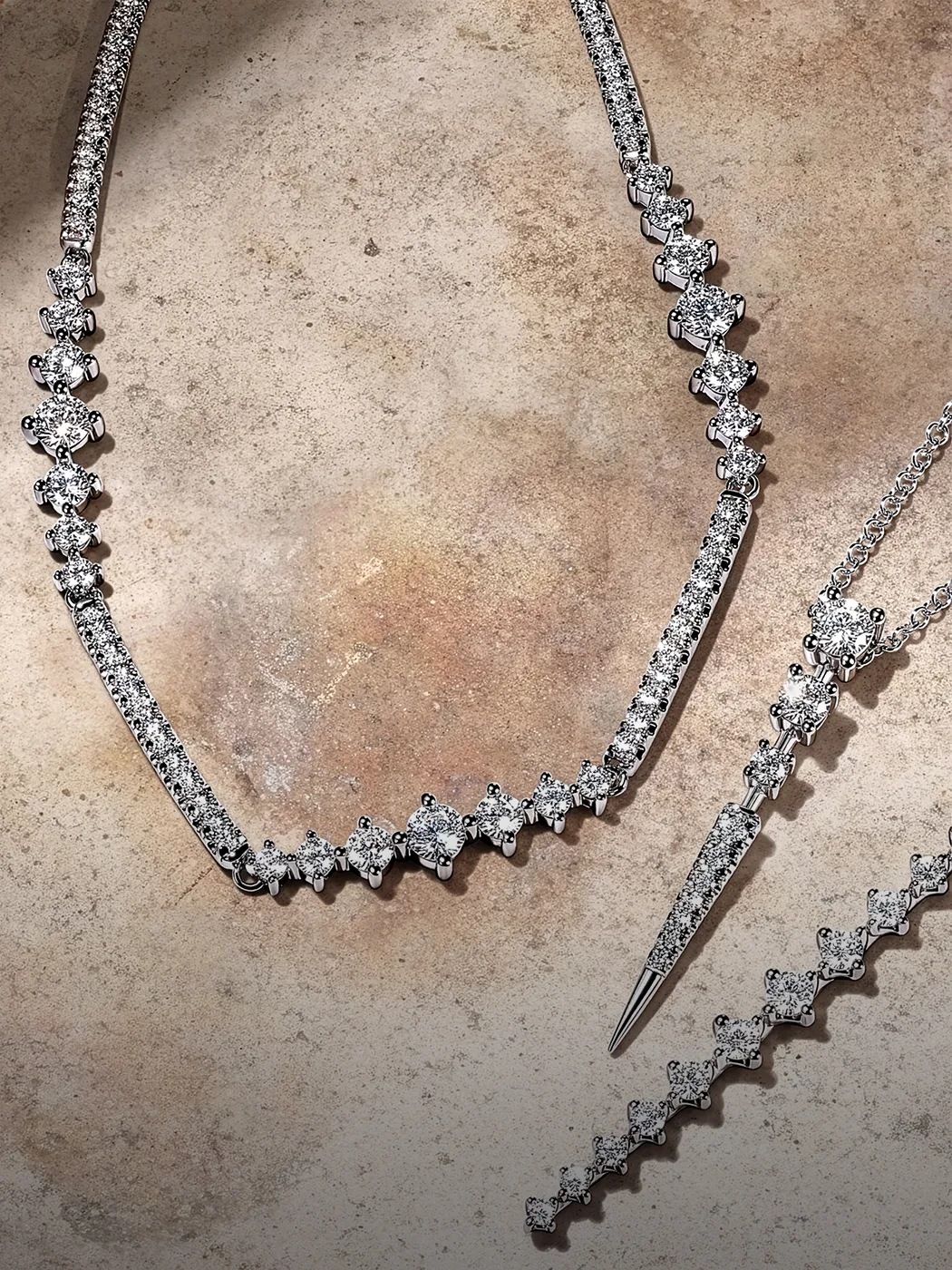 Natural diamond necklaces displayed on a textured surface at McGee & Company Fine Jewelers.