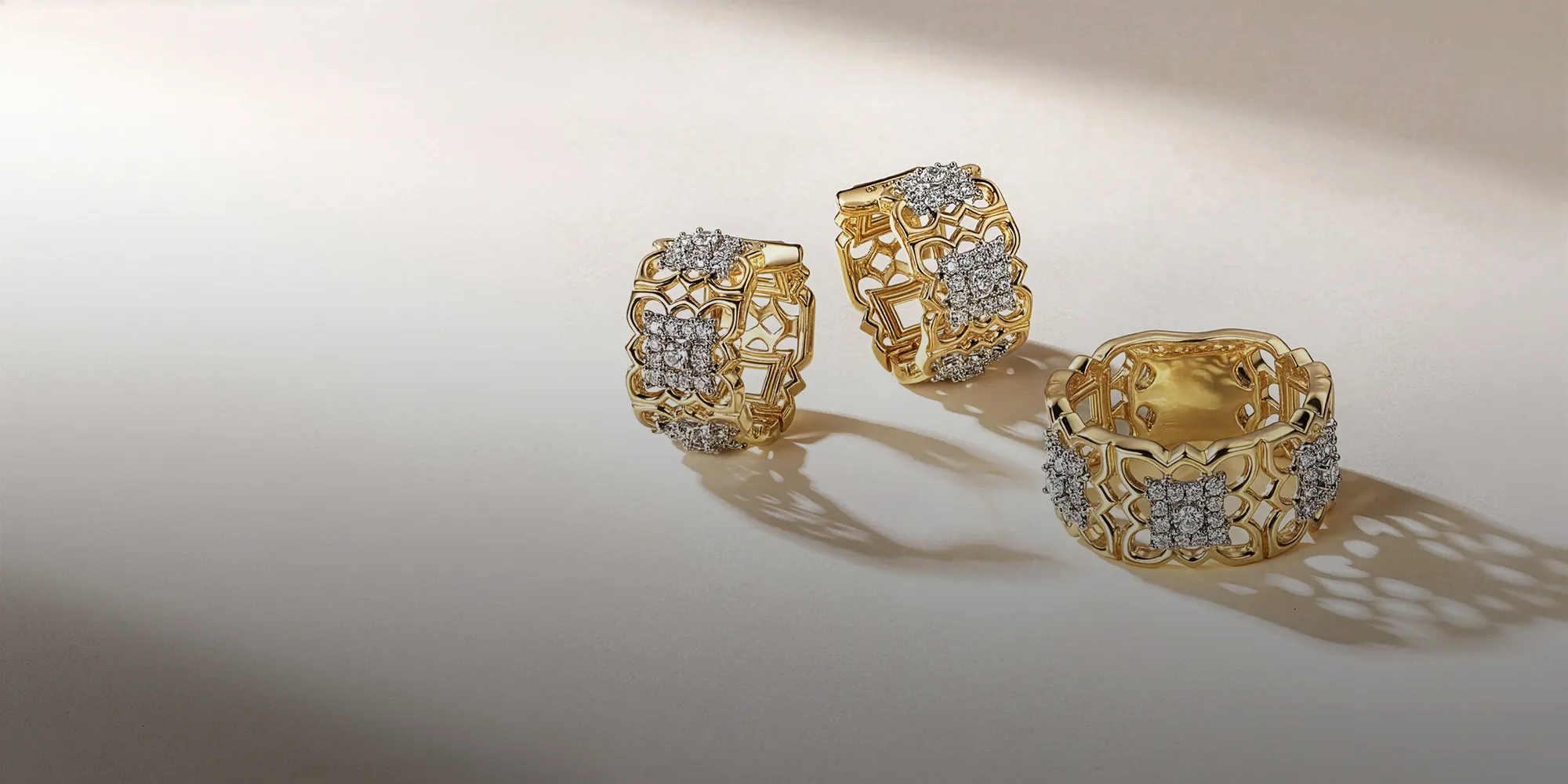 Elegant gold rings with intricate designs and diamond accents on a soft background. Book an Appointment at McGee & Company Fine