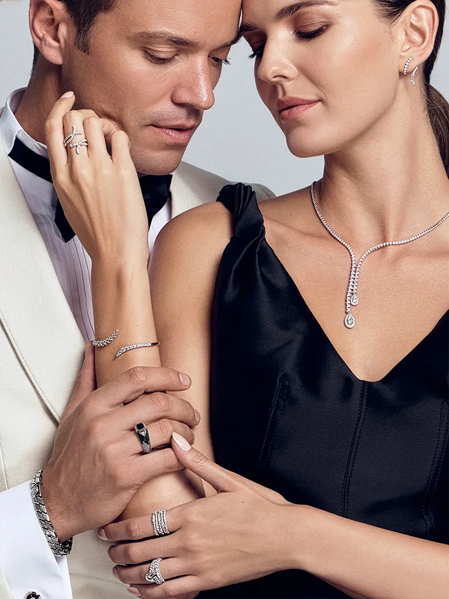 A couple elegantly showcases fine jewelry, including rings, a necklace, and a bracelet.