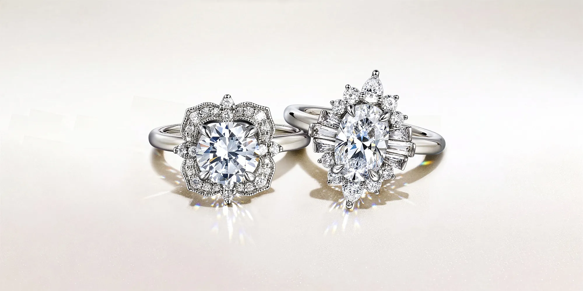 Two elegant diamond rings with intricate settings on a light background.