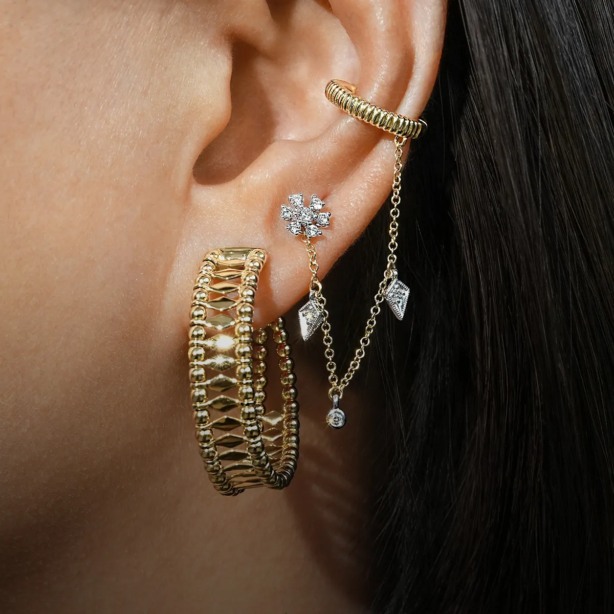 Gold and diamond earrings with chains and studs on an ear. Explore Gabriel & Co earrings at McGee & Company.