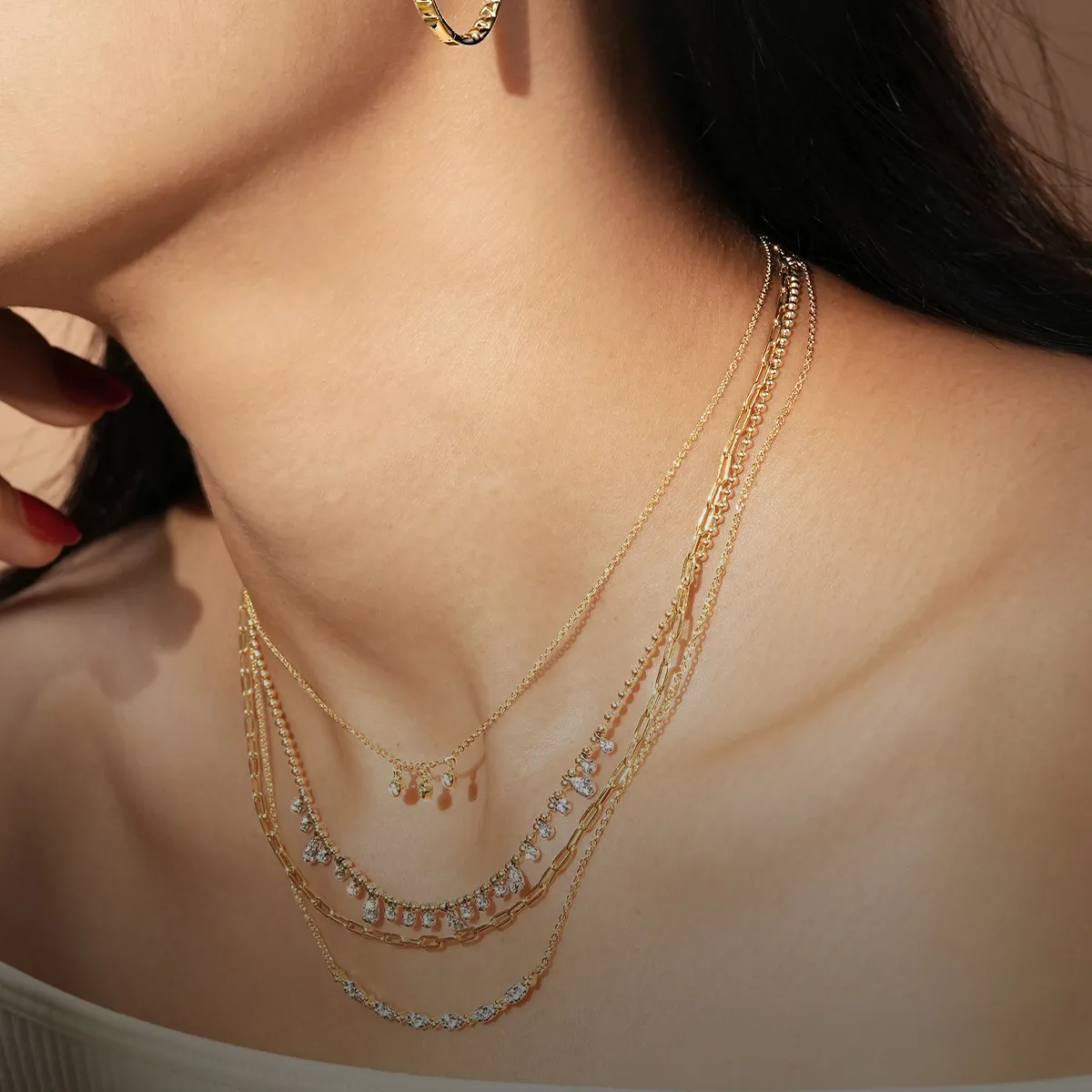 Layered gold necklaces with gemstones on a woman's neck.