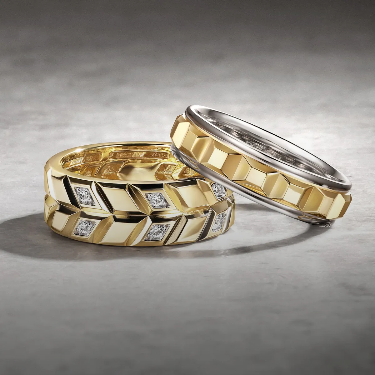 Gold and silver geometric wedding bands with diamonds on a textured surface.