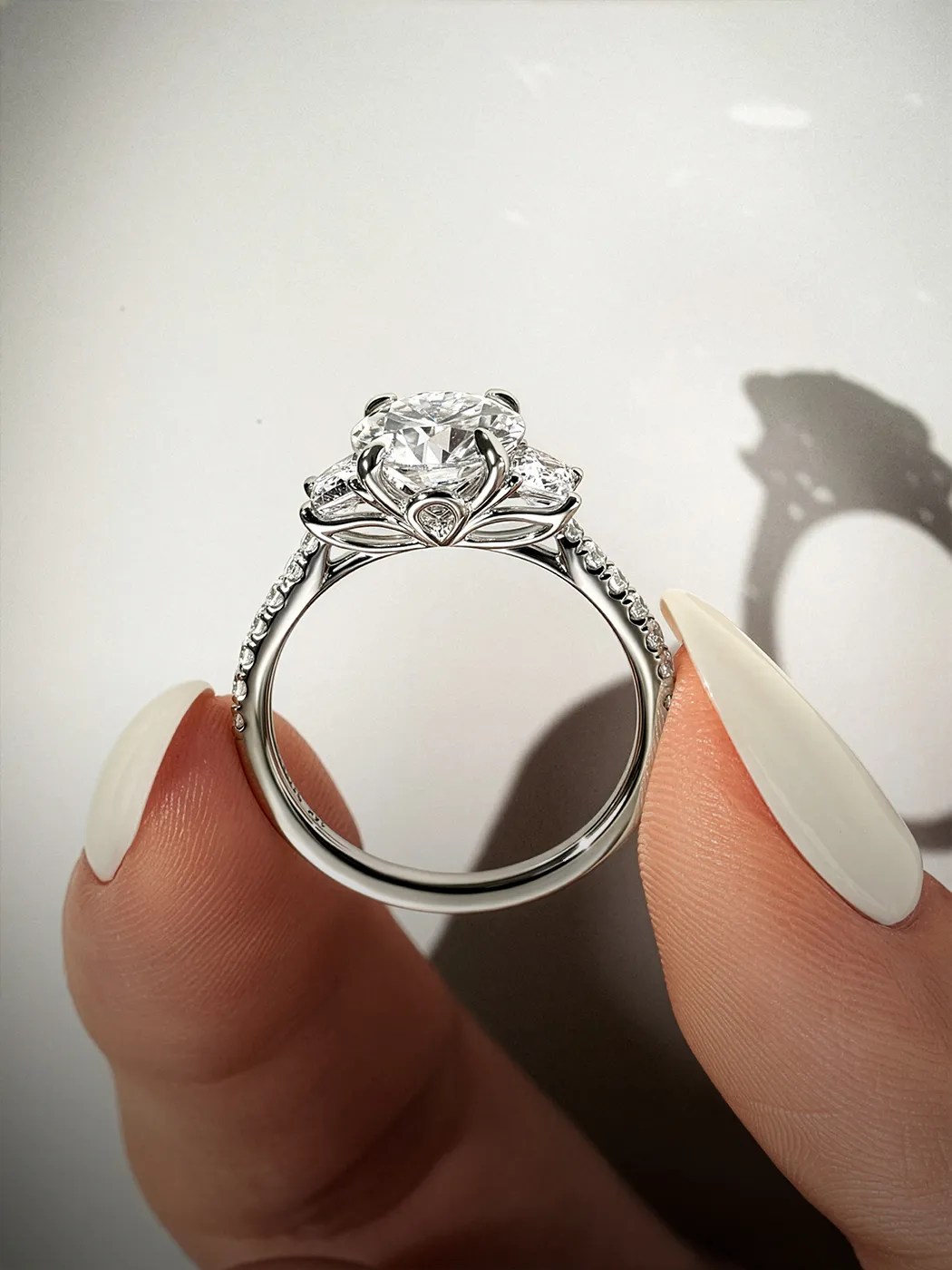 Diamond engagement ring with intricate setting held between fingers.
