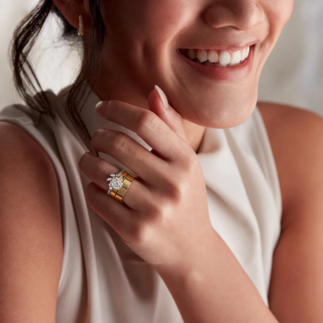 Smiling woman wearing gold and diamond rings, showcasing jewelry.